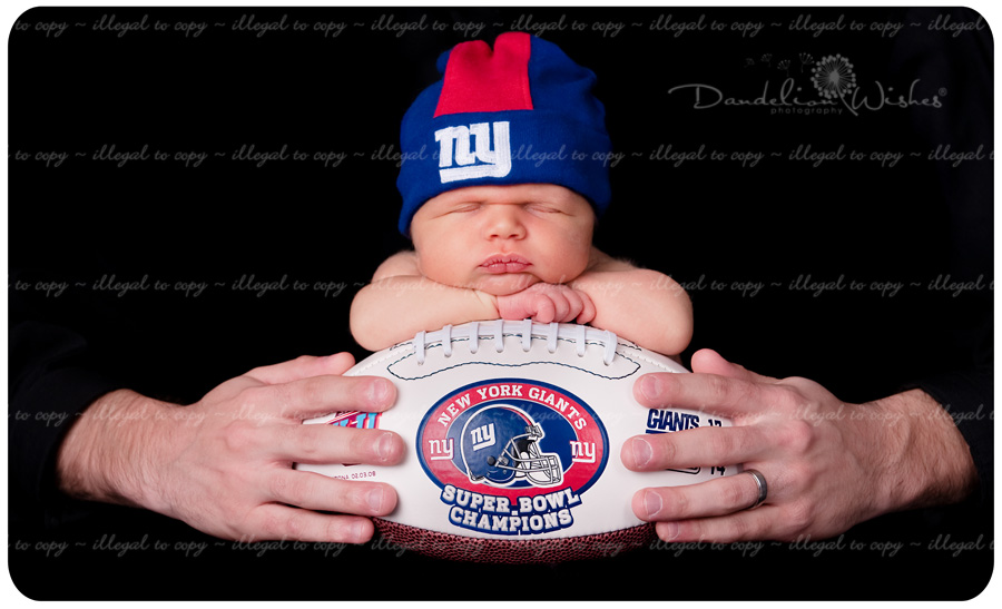 Unique photo of newborn baby on New York Giants football ~ Professional photographers in Northern Virginia near Bristow VA. New York Giants fans from Bristow - Gainesville, Virginia. Newborn baby on football.